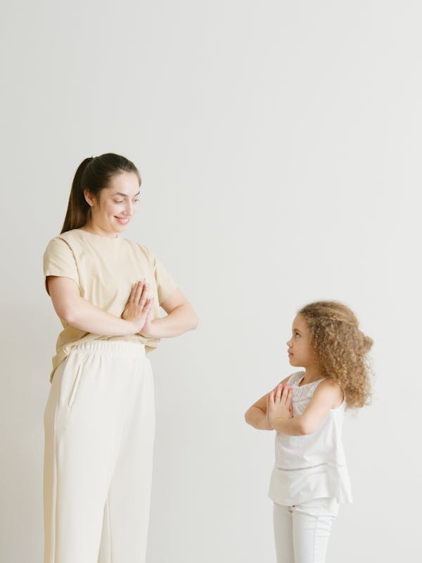 A mother and daughter practicing yoga together indoors, promoting a healthy and relaxed lifestyle.